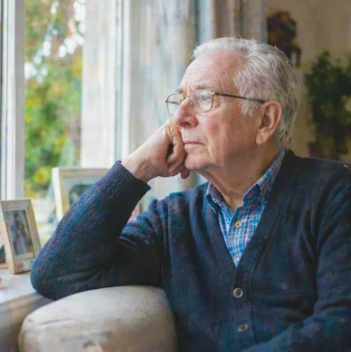 An older man sitting alone by the window